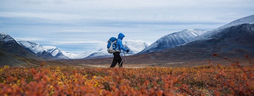 hiker with snow covered mountains and autumn colors in southern end of Tjäktjavagge on Kungsleden trail, Lappland, Sweden